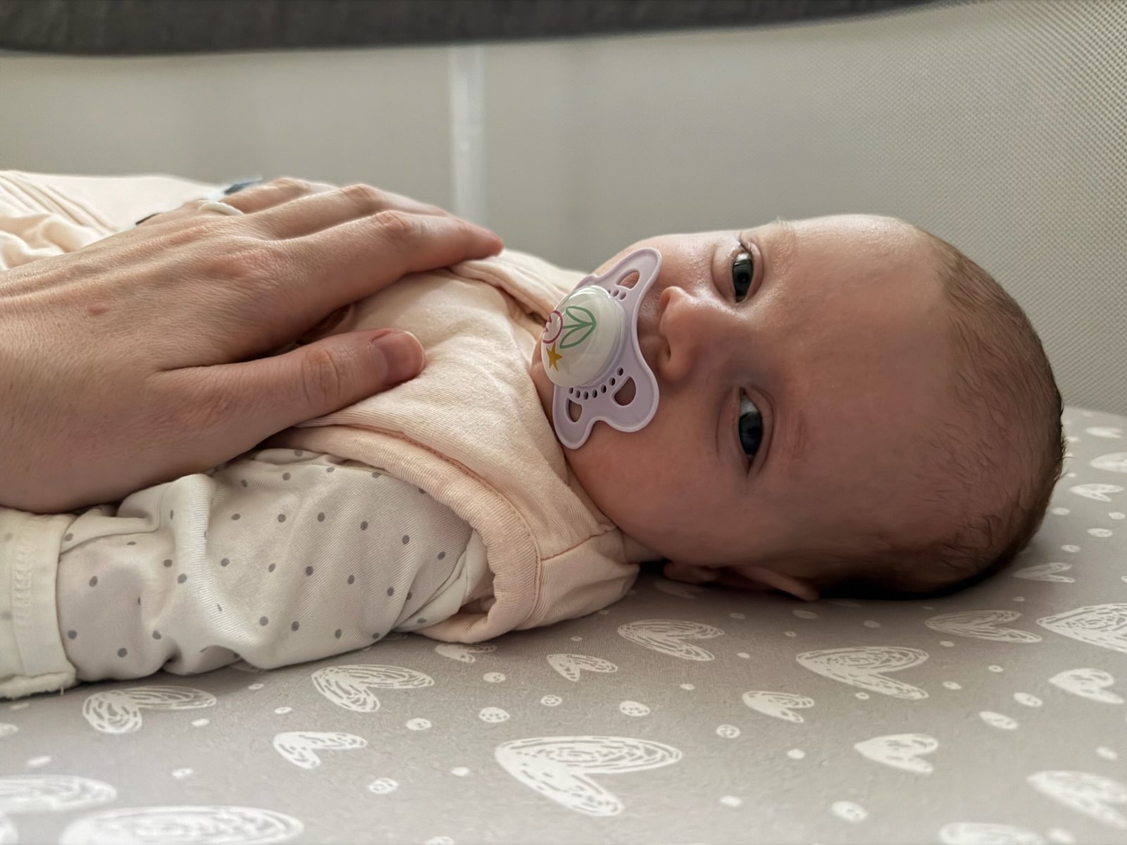 Newborn resting in a bassinet with a pacifier, supported by You Can Doula Services